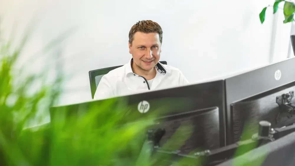 Medewerker Verkoopadministratie achter bureau met twee grote schermen